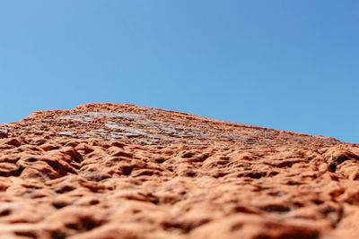 Low angle view of stone wall against clear blue sky