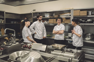 Female chef talking to coworkers in commercial kitchen