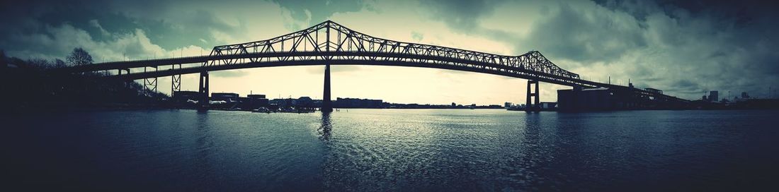 Bridge over river against cloudy sky