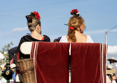 Rear view of women sitting against sky