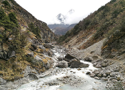 Scenic view of stream amidst rocks against sky