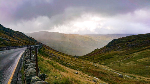 Scenic view of road leading towards mountains against sky