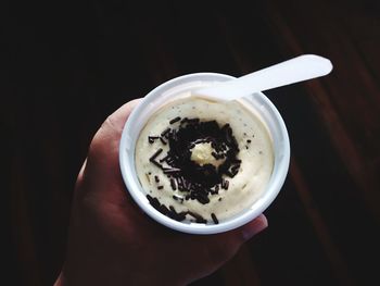 Hand holding coffee cup against black background