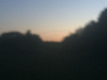 Defocused image of silhouette landscape against sky during sunset