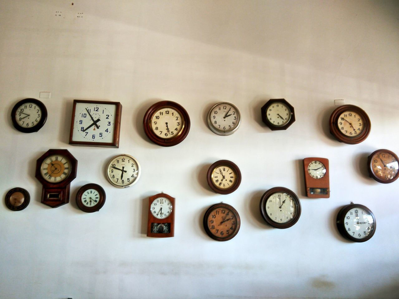 CLOSE-UP OF VARIOUS CLOCK ON WHITE WALL