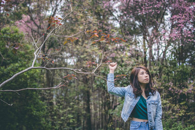 Beautiful woman looking away while standing against pink flowering tree