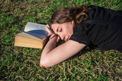 Woman sleeping by book on grass