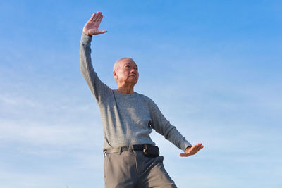 Low angle view of man with arms raised against sky