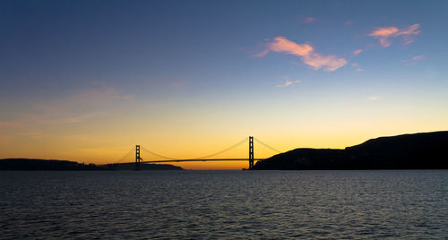 Silhouette golden gate bridge over sea against sky during sunset