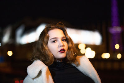 Portrait of young woman standing outdoors at night