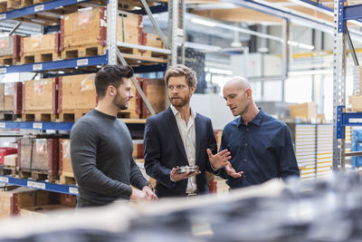 Three men talking in factory storeroom