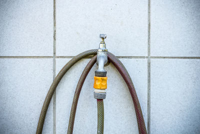 Close-up of garden hose and faucet against wall