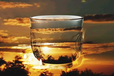 Close-up of beer glass against orange sunset sky
