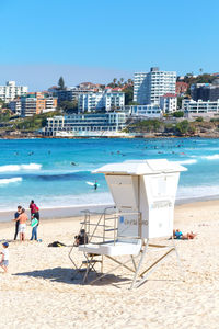 People on beach by sea against blue sky