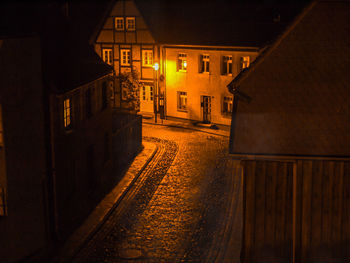 Empty road amidst illuminated buildings at night