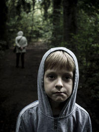 Portrait of boy standing on dirt road at forest