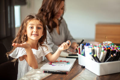 Portrait of girl drawing while sitting with mother