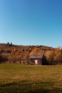 Houses on field against clear blue sky