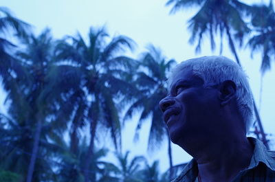 Low angle view of man looking away against trees and sky