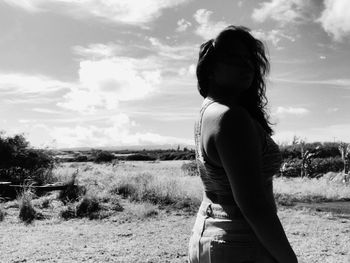 Rear view of woman standing on field against sky