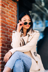 Portrait of beautiful young woman against brick wall