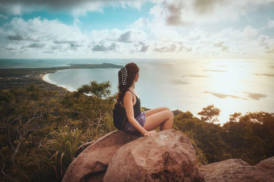 Woman sitting on rock looking at sea against sky in mexico