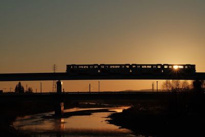 Silhouette bridge over lake against sky during sunset