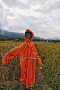 Rear view of woman walking on field against sky