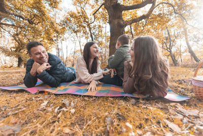 Group of people sitting at park during autumn