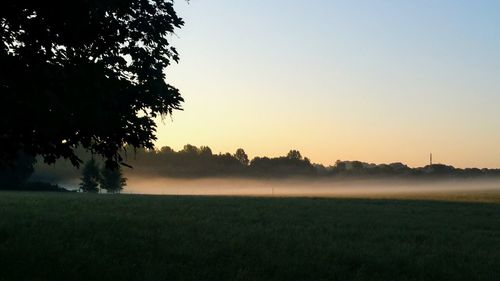 Scenic view of field against clear sky during sunset