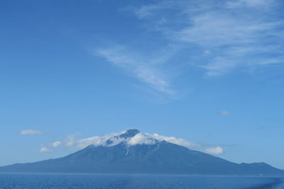 Scenic view of sea and mountains against blue sky