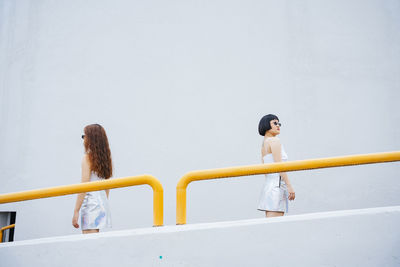 Woman standing by railing against sky