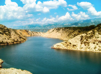 Scenic view of river by mountains against sky