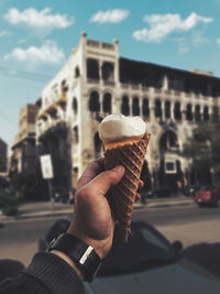 Cropped hand of man having ice cream cone in city