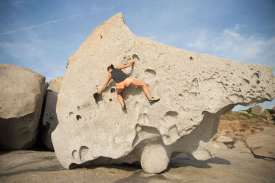 Rear view full length of woman climbing rock