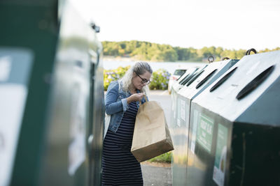 Blond woman throwing rubbish into waste bin