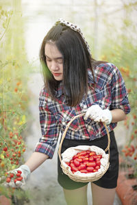 Woman holding strawberry while standing on plant