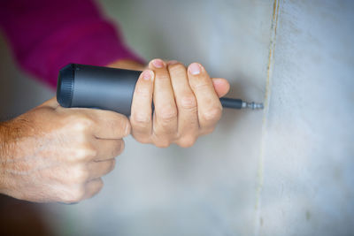 Close-up of man holding cigarette against wall