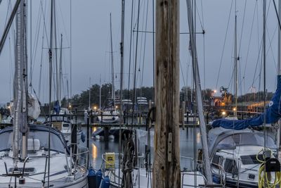 Boats moored at harbor against sky during dusk