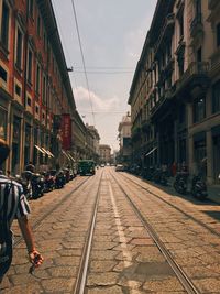 Railroad track on street amidst buildings in city during sunny day