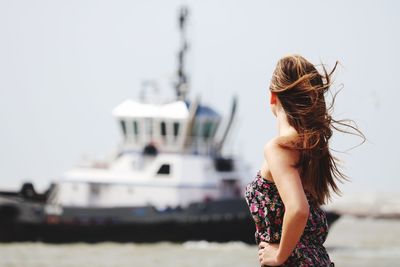 Rear view of young woman standing against clear sky