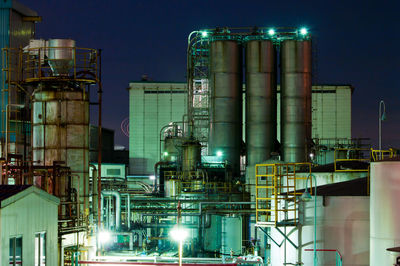 Illuminated factory against sky at night