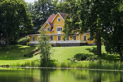 House by lake against trees and building