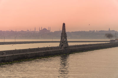 View of river by building against sky during sunset