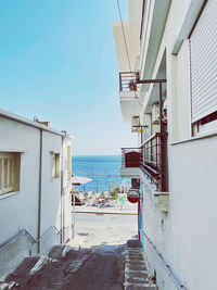 Buildings by sea against clear blue sky