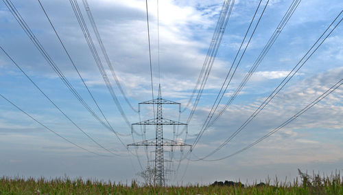 Low angle view of electricity pylon on field against sky