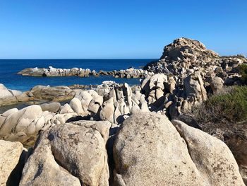 Rocks on beach against clear blue sky