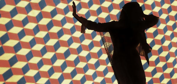 Woman standing against illuminated background with geometric pattern