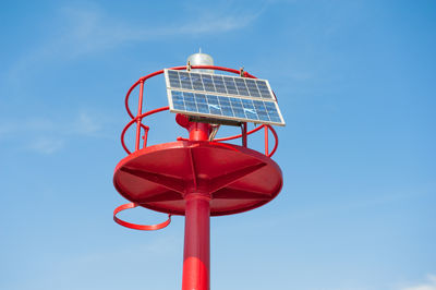 Low angle view of solar panel attached to red lighthouse against sky