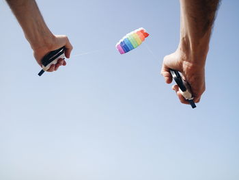 Low angle view of person holding handles of parachute